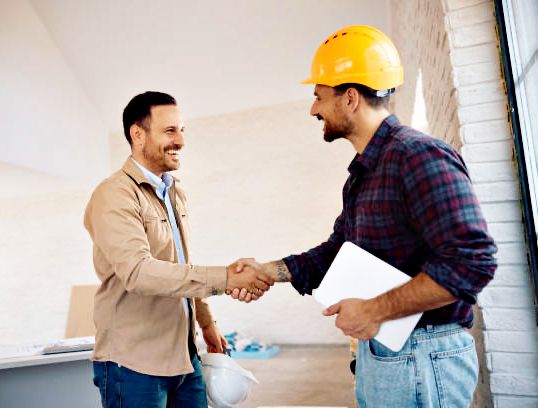 happy worker and his clients shaking hands at constriction site. copy space. happy worker and his clients shaking hands at constriction site. copy space.
